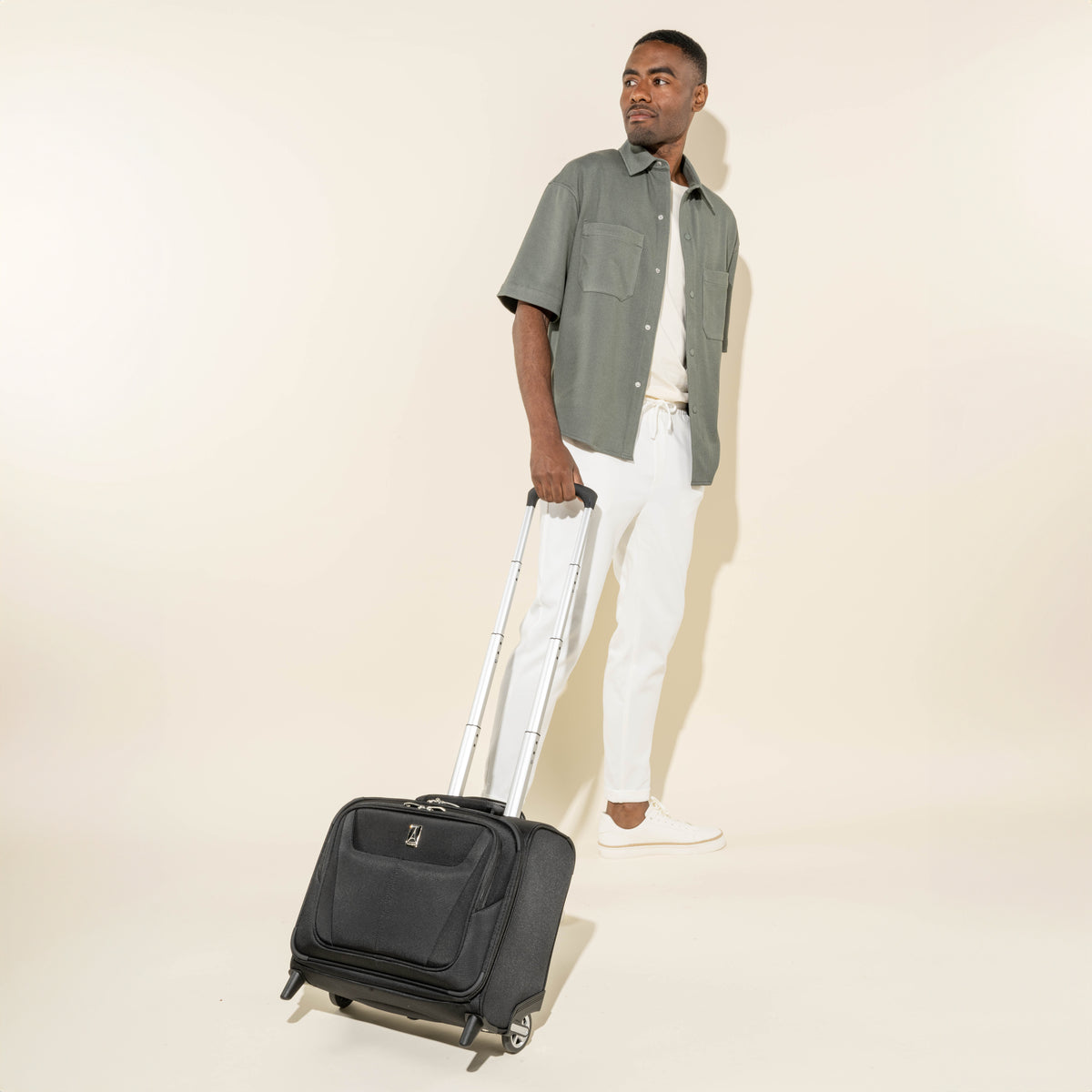 lifestyle view of a man pulling the black travelpro maxlite 5 carry-on rolling tote by its extended powerscope lite handle, demonstrating its compact size and mobility for short trips.