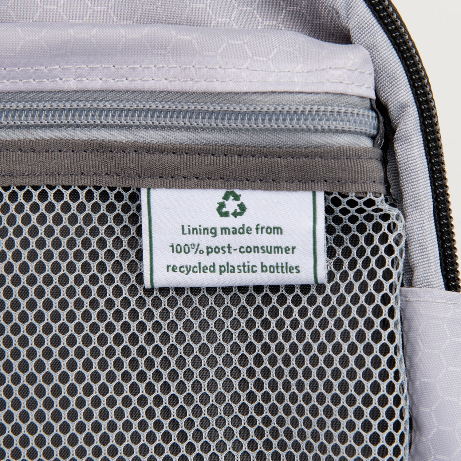close up of the interior fabric tag on the black travelpro maxlite 5 carry-on rolling tote showing a green recycling symbol and text stating lining made from 100 percent post-consumer recycled plastic bottles.