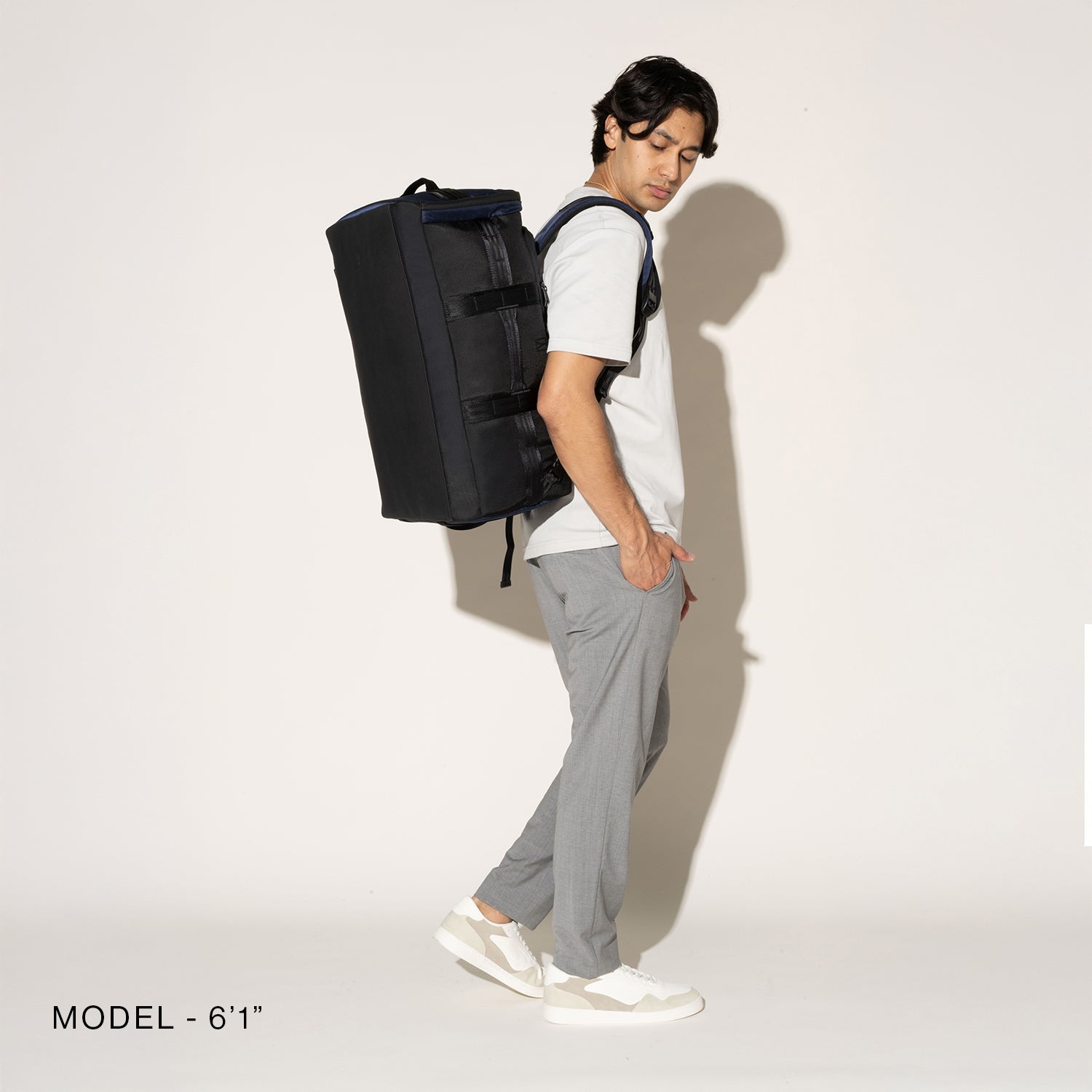 Person wearing a black convertible duffel on a white background