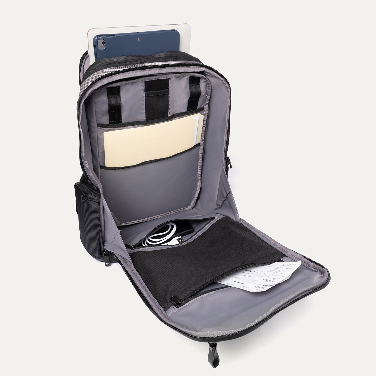 Gray backpack with compartments containing a tablet, notebook, and other items on a white background