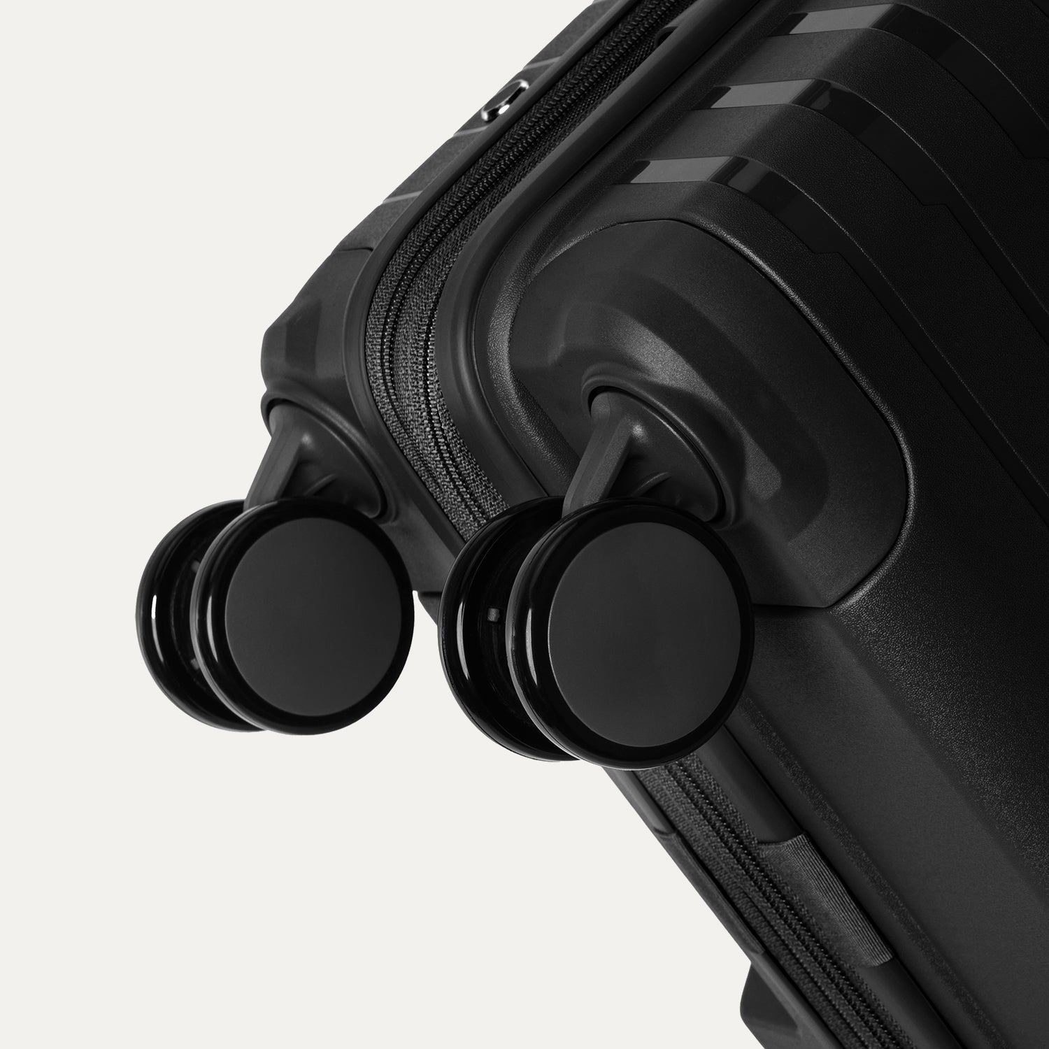 Close-up detail view of the Optima® Expandable Compact Carry-on Spinner in Black, showcasing the durable base construction and smooth-rolling, self-aligning MagnaTrac® spinner wheels.