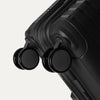 Close-up detail view of the Optima® Expandable Compact Carry-on Spinner in Black, showcasing the durable base construction and smooth-rolling, self-aligning MagnaTrac® spinner wheels.