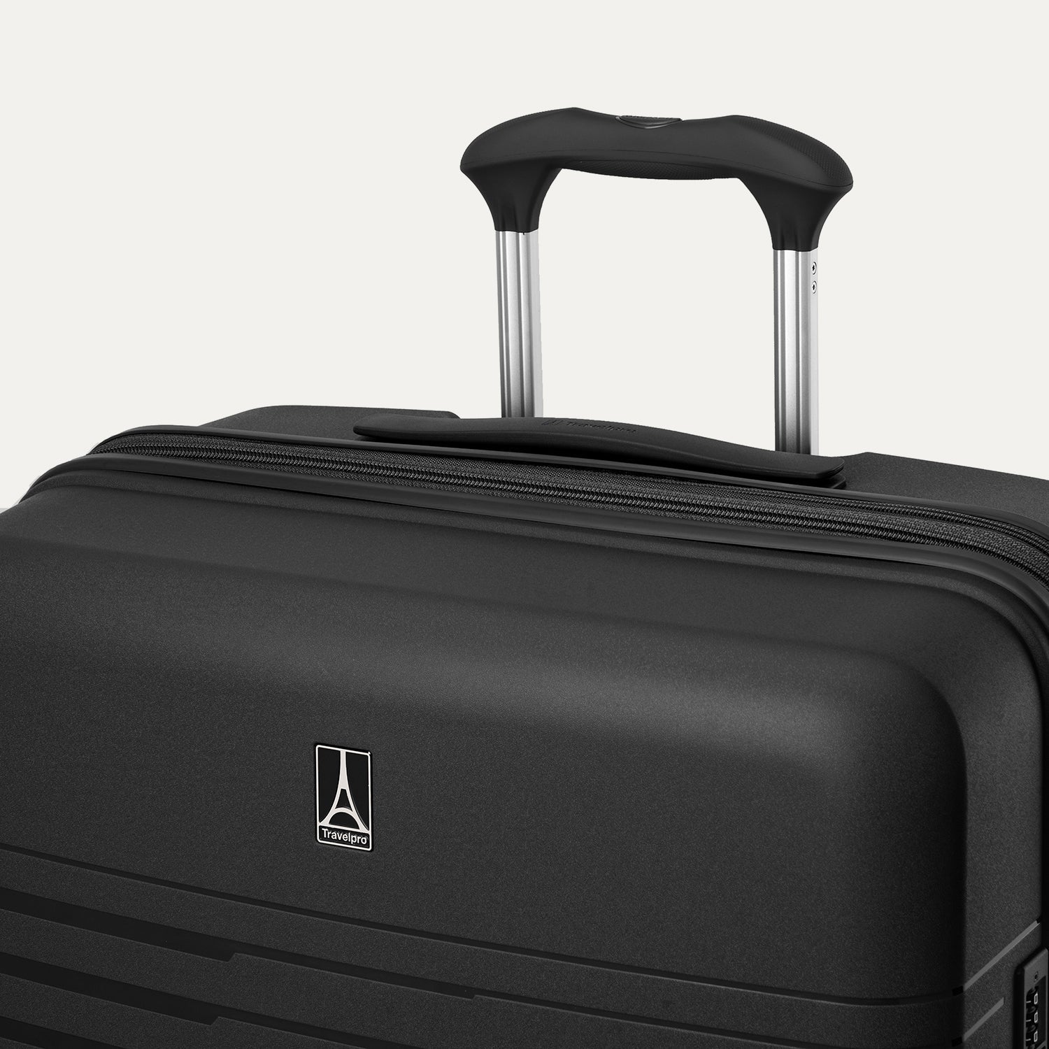 Close-up detail view of the top of the Optima Expandable Large Check-in Spinner in Black, highlighting the extended PowerScope handle, top carry handle, and Travelpro branding on the hardside shell.